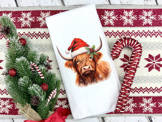 Highland Cow wearing a santa hat on a tea towel as a Christmas gift