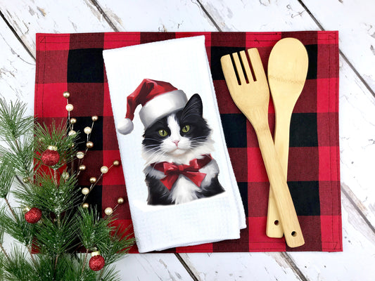 Tuxedo cat wearing a santa hat on a tea towel